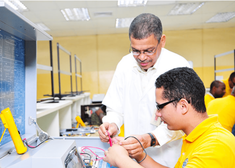 Profesor guiando a un estudiante en una práctica de electrónica en un laboratorio
