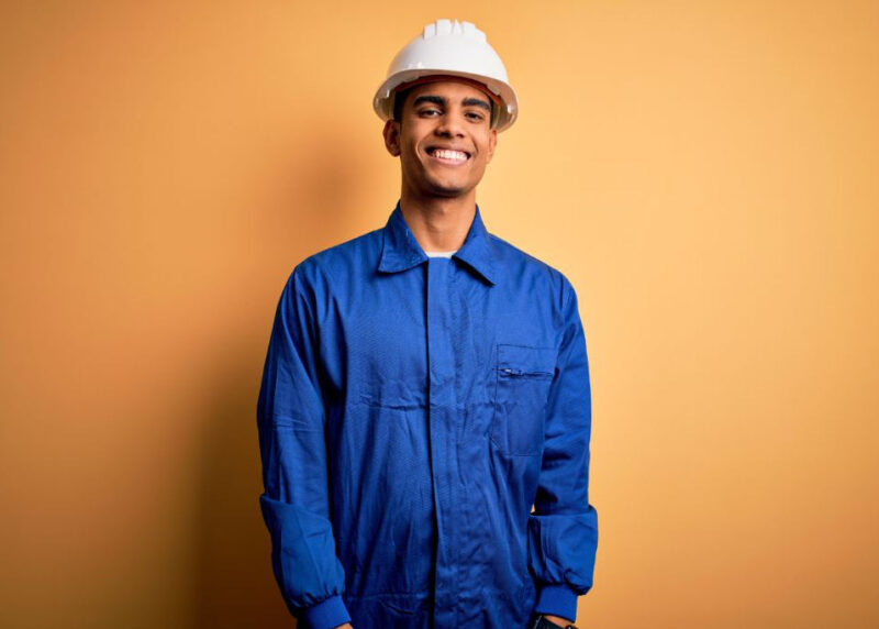 Hombre joven con casco blanco y uniforme azul sonriendo