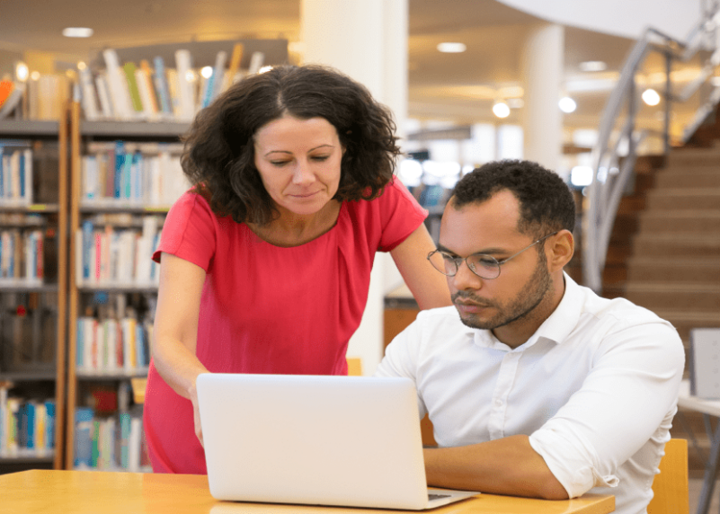 Una mujer con una camisa blanca, sonriendo y de pie en un entorno luminoso y acogedor.