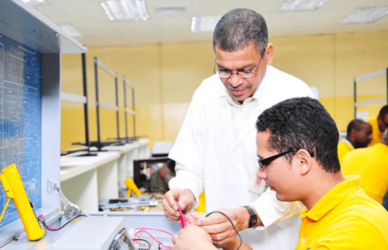 Profesor guiando a un estudiante en una práctica de electrónica en un laboratorio