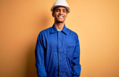 Hombre joven con casco blanco y uniforme azul sonriendo