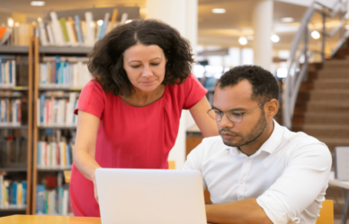 Una mujer con una camisa blanca, sonriendo y de pie en un entorno luminoso y acogedor.